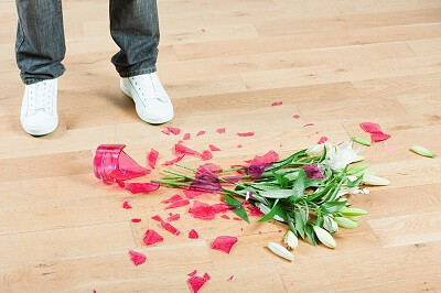 View of person's feet standing next to a broken flower vase
