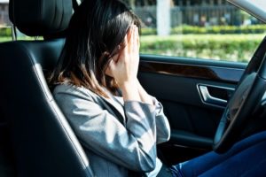 Woman sitting in the driver's seat of her car, crying